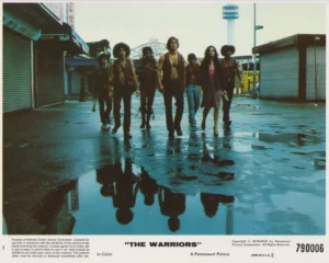 A vintage cinema lobby card featuring a scene from The Warriors (1979)